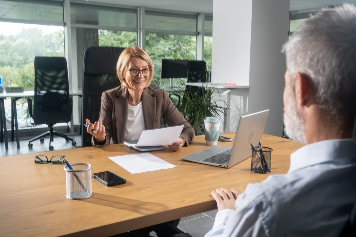 Insurance agent smiling and reviewing a policy with a client in a bright office